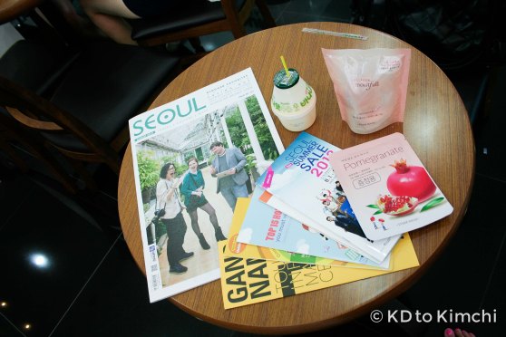 My swag: coupon book for the 2013 Seoul Summer Sale, a copy of SEOUL Magazine with Mimsie Ladner of "Seoul Searching" blog on the cover, free cosmetics, and a free banana milk